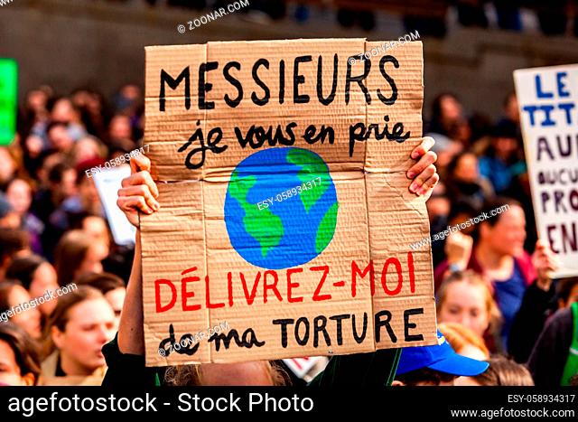 A close up view of a French sign, saying gentlemen, please release me from my torture, held by a climate change campaigner during a city protest
