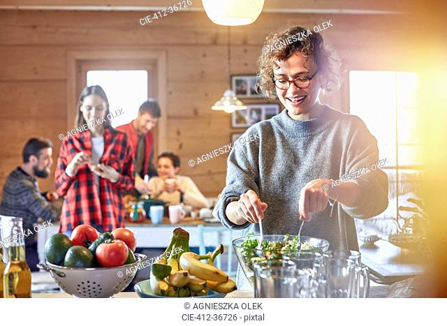 Woman tossing salad for friends in cabin