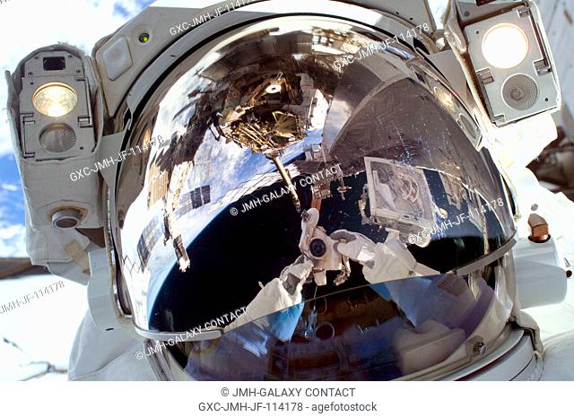 Astronaut Robert L. Satcher Jr., STS-129 mission specialist, uses a digital still camera to expose a photo of his helmet visor during the mission's first...
