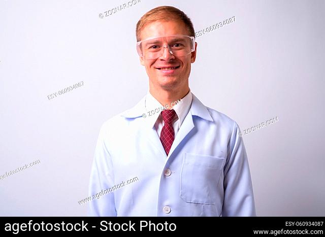 Studio shot of handsome man doctor as scientist wearing protective glasses against white background