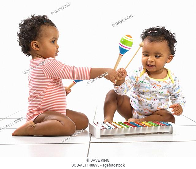 Twin boy and girl (18 months) playing with xylophones and maracas