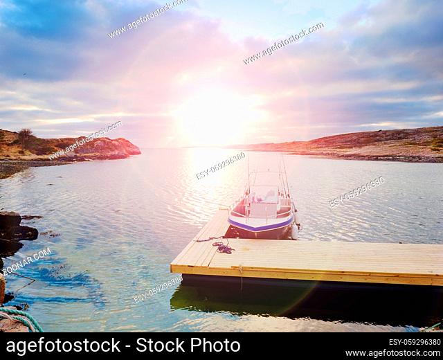 Fishing boat at sunset calm water. A motorboat for sport fishing tied to a wooden floating dock