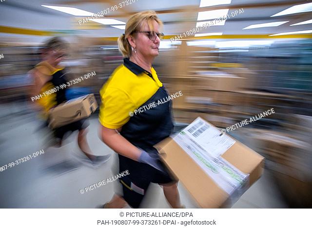 07 August 2019, Mecklenburg-Western Pomerania, Wittenburg: Parcel carrier Sabine Weiß sorts parcels for her tour at Deutsche Post's delivery base