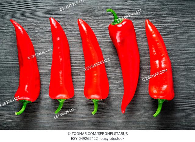 Five ripe sweet red Kapia peppers on dark shale stone background