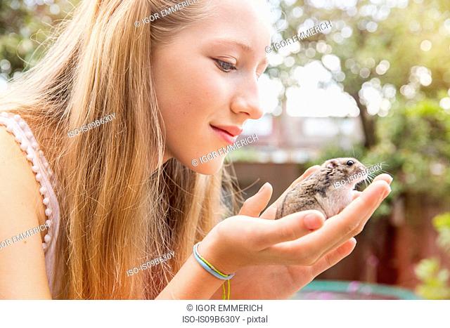Teenage girl holding hamster