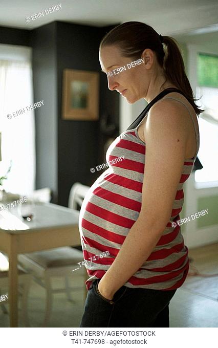 A pregnant woman in her kitchen in her 27th week of pregnancy