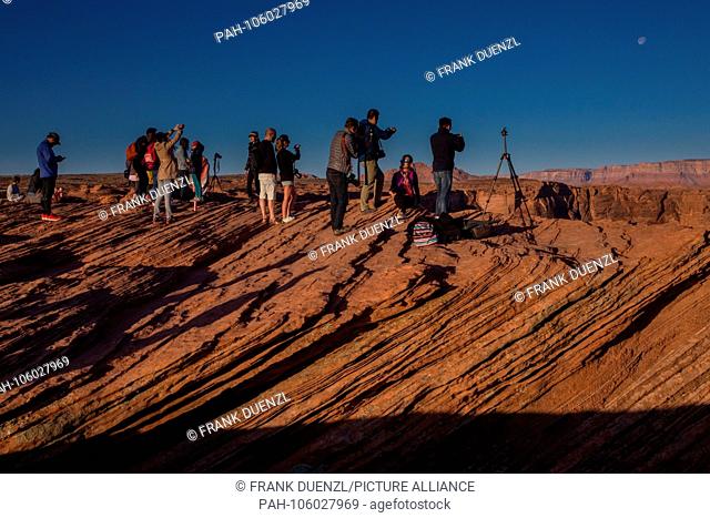 Tourists with cameras and tripods at sunrise at Horseshoe Bend in Arizona, where the Colorado River takes a sharp U-turn, in March 2018