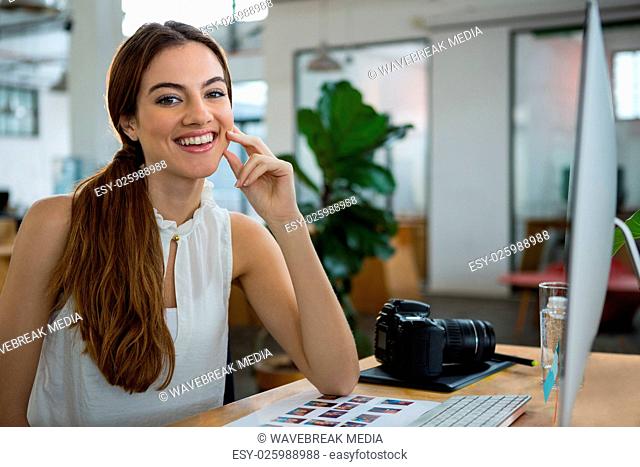 Smiling female graphic designer sitting at desk