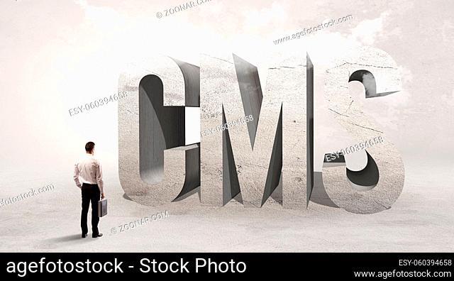 Rear view of a businessman standing in front of CMS abbreviation, attention making concept
