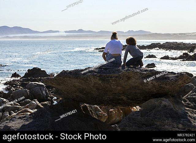 Teenage girl and younger brother hiking on a coastal trail by the ocean