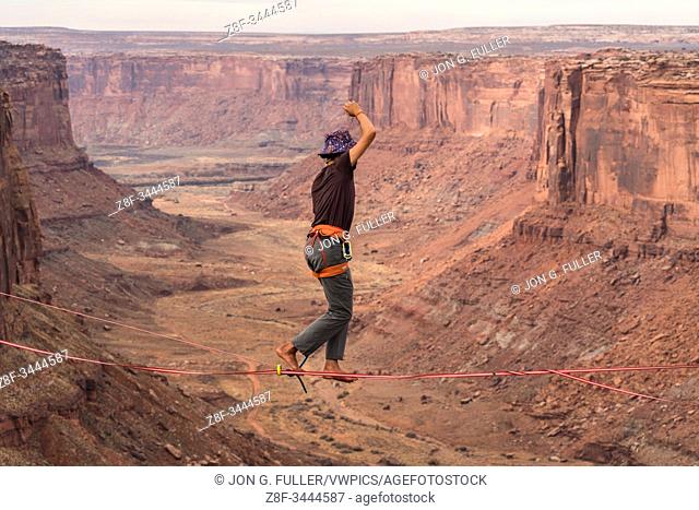 A young man slacklining or highlining hundreds of feet above Mineral Canyon near Moab, Utah during a highline gathering
