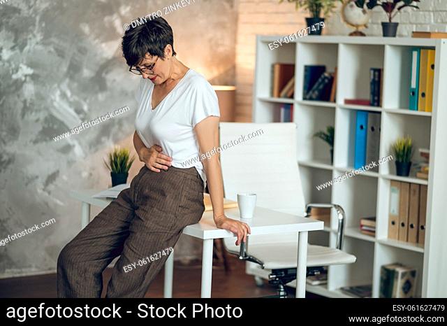 Menopause. Mature short-haired woman suffering from pains in stomach