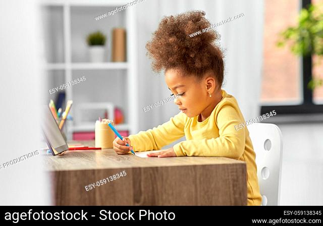 little girl with felt pen drawing picture at home