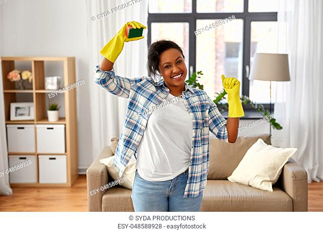 happy african woman with sponge cleaning at home