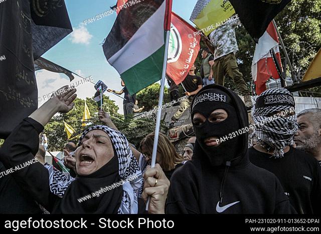 20 October 2023, Lebanon, Beirut: A Palestinian woman chants slogans near two hooded Palestinian youth from the Islamic Jihad during a demonstration to support...