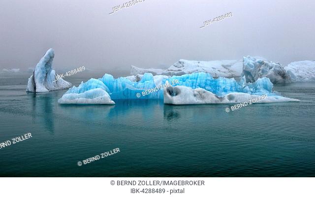 Drifting blue icebergs in the Jökulsárlón glacier lagoon in fog, Southern Region, Iceland