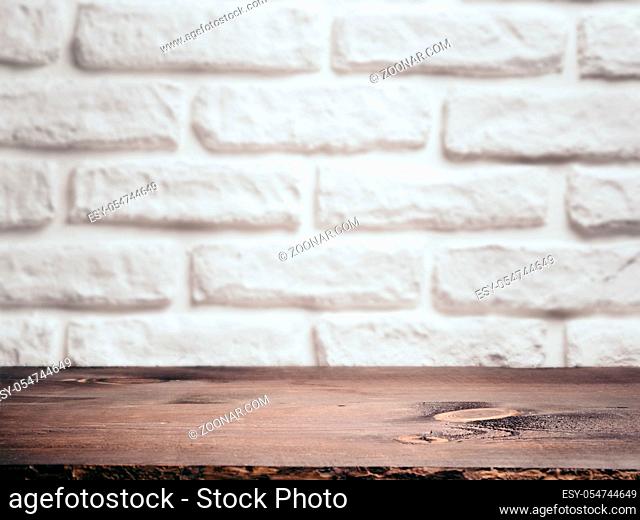 Empty wooden table and white brick wall as background. Brown wooden background for mock up