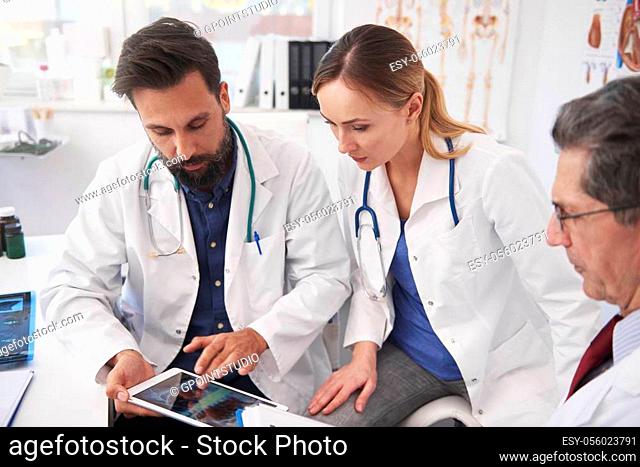 Three doctor working with tablet in doctor's office