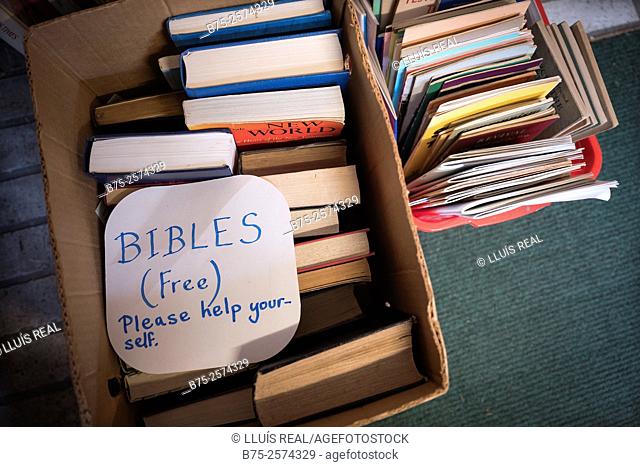 Cardboard box full of bibles in a second hand book shop with a sign handwritten: Bibles, free, please help yourself. Settle, Yorkshire Dales, North Yorkshire