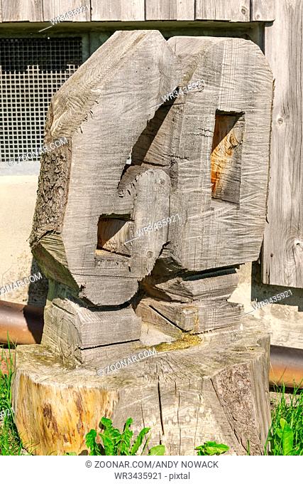 Aus einem Baumstumpf geschnitzte Zahl 60 vor einer Scheune im Gras. Number 60 carved from a tree stump in front of a barn in the grass