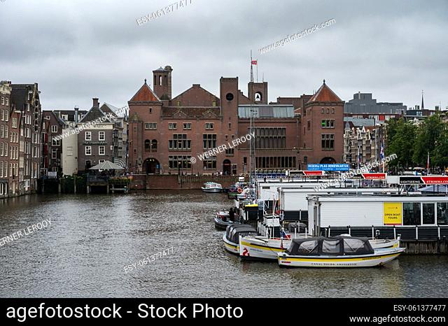 Amsterdam, North Holland, The Netherlands - Cityscape view over boats at the Damrak canal and historical buildings in old town