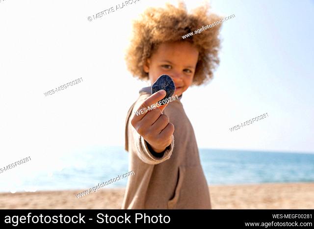 Girl holding stone standing in front of sea at beach