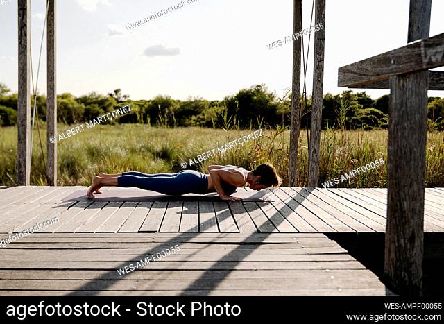 Woman in sports clothing doing yoga at gazebo