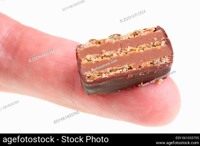 In the future we will eat this concept - little ugly slice of chocolate cake on finger. Isolated on white studio macro