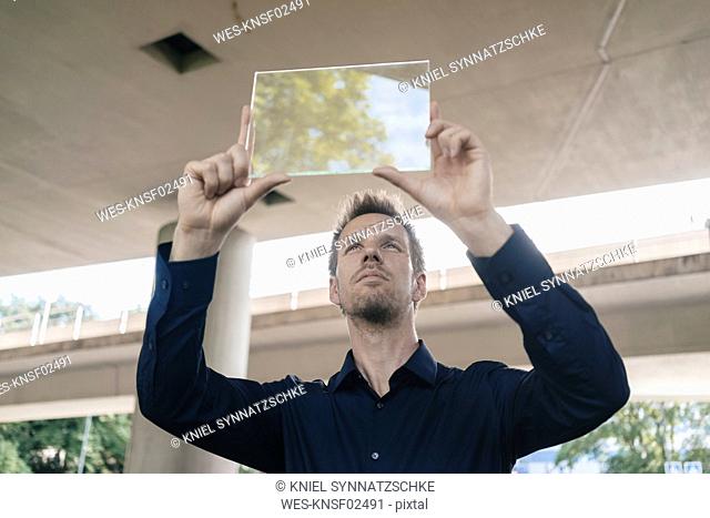 Businessman holding up portable glass device