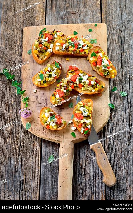 Warmes Fingerfood: Leckere Crostini mit Feta-Grillgemüse und Olivenöl - Warm canapes: Baked crostini with mixed Greek vegetables with feta cheese served on a...