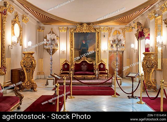 Cairo, Egypt - December 2, 2017: Throne Hall at Manial Palace of Prince Mohammed Ali Tewfik with gold plated red armchairs, antique floor lamps