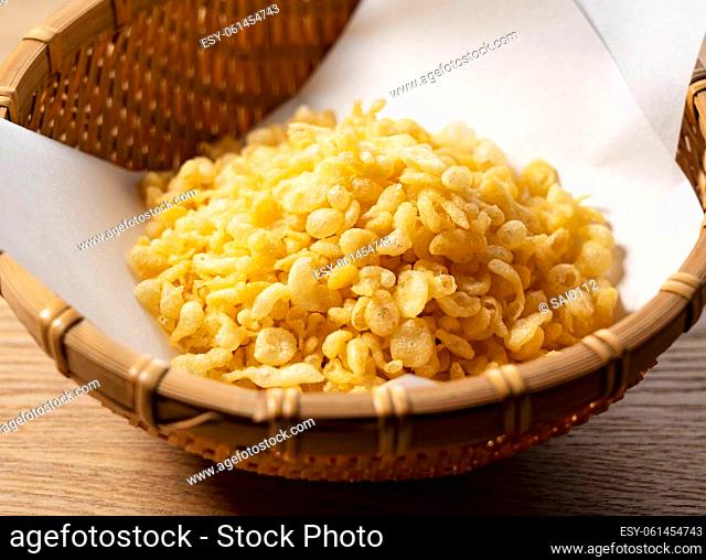 Tenkasu served in a colander placed against a wooden background. Image of Japanese food