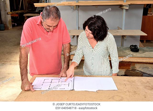 woman looking at the blueprints of a project in the carpenter's workshop