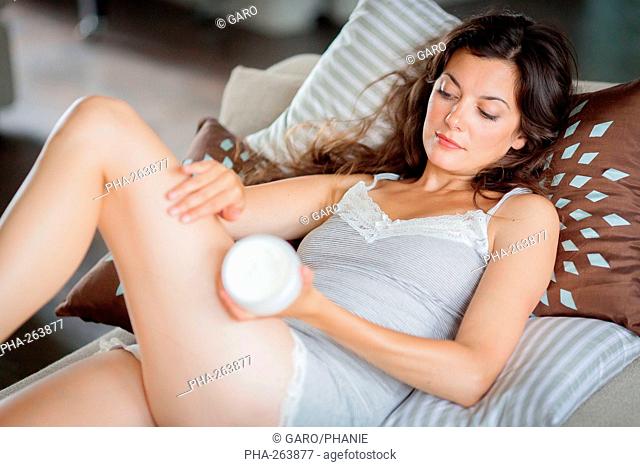 Woman applying cream on her legs