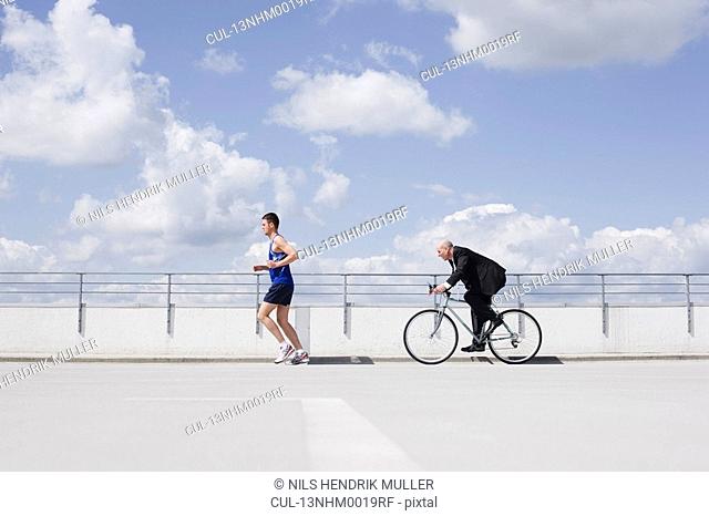 man with bycicle chasing jogger