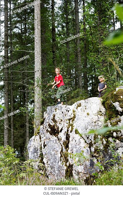 Brother and sister playing on rock formation in forest, Zauberwald, Bavaria, Germany