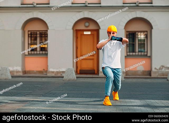 Young disabled karate man with artificial prosthetic hand in casual clothes at outdoor city street. Martial arts concept