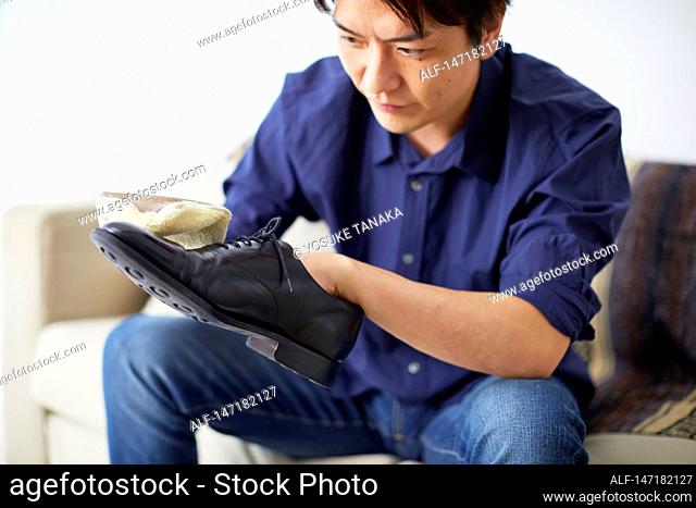 Japanese man cleaning shoes at home