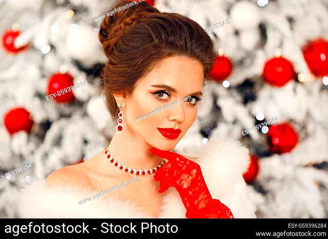 Bride portrait of Elegant woman with ruby jewelry set and red gloves. Beautiful brunette lady with wedding hairstyle, beauty makeup wears posing over xmas tree...