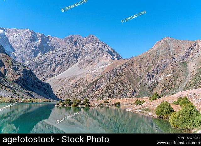 The Pamir range view and peaceful campsite on Kulikalon lake in Fann mountains in Tajikistan. Amasing colorful reflection in pure ice lake