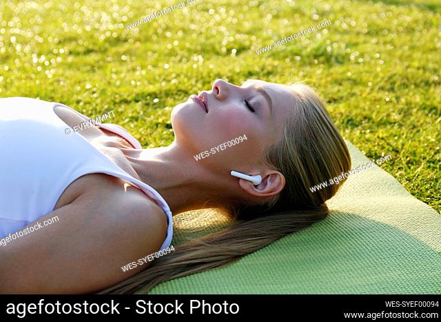Woman with eyes closed lying on exercise mat