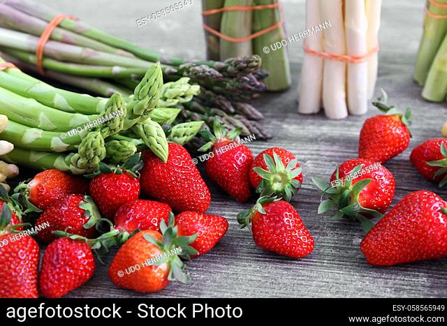 Green asparagus, white asparagus and fresh strawberries decorated on a rustic wooden table