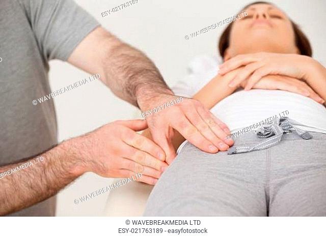 Woman lying while a physiotherapist massaging her thigh in a room