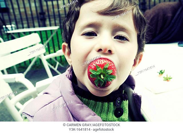 Little girl eating strawberries. London