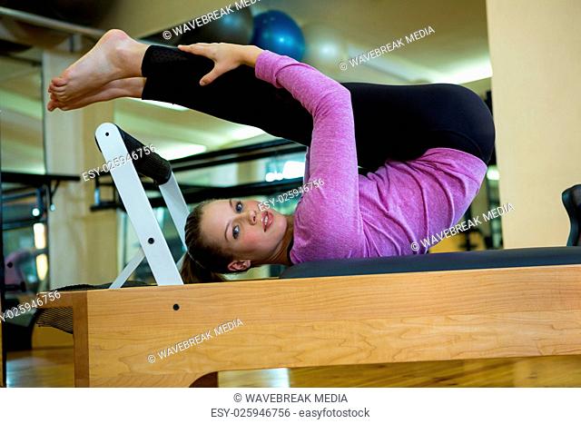 Portrait of beautiful woman performing stretching exercise on reformer