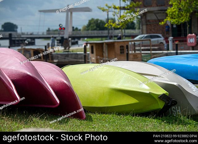 19 August 2021, Mecklenburg-Western Pomerania, Loitz: Canoes are moored on the banks of the Peene in Loitz harbour. Various boat rental companies offer guided...