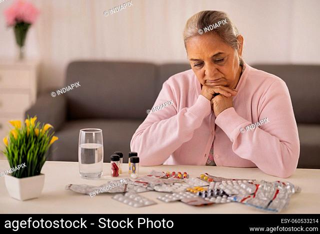 Old woman going to take medicine kept on centre table