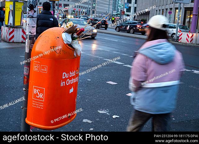 19 November 2023, Berlin: 19.11.2022, Berlin. A BSR rubbish bin at Potsdamer Platz is overflowing as tourists and Berliners walk past