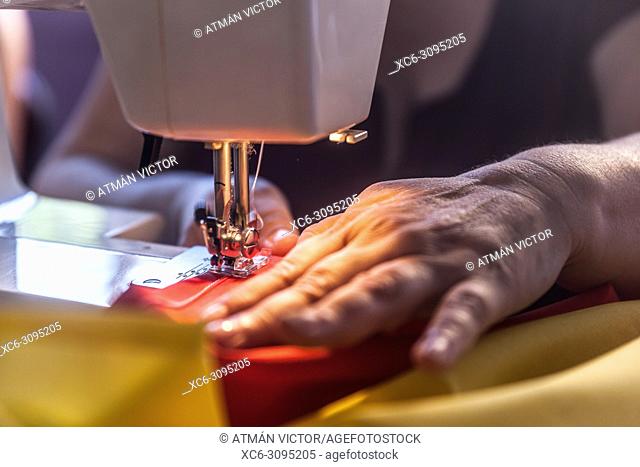 adult woman sewing the spanish flag with a SINGER brand sewing machine. Tenerife island