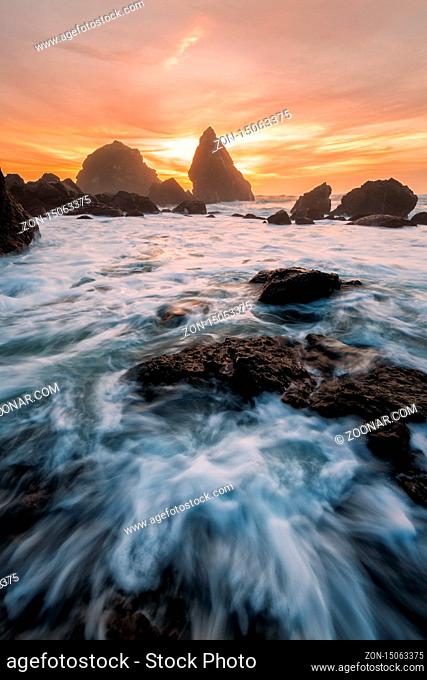 Sunset at a rocky beach with vivid warm colors and beautiful skies